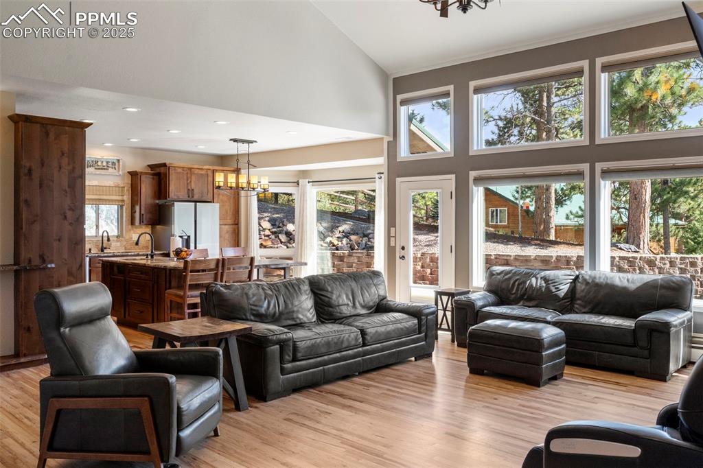 Image 4 of 46: Living area with a chandelier, high vaulted ceiling, light wood-style floor