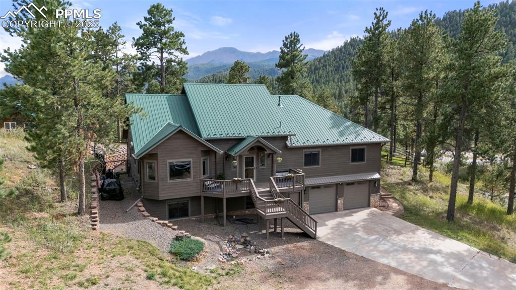 Image 40 of 46: View of front facade with stairway, a deck with mountain view, a metal roof