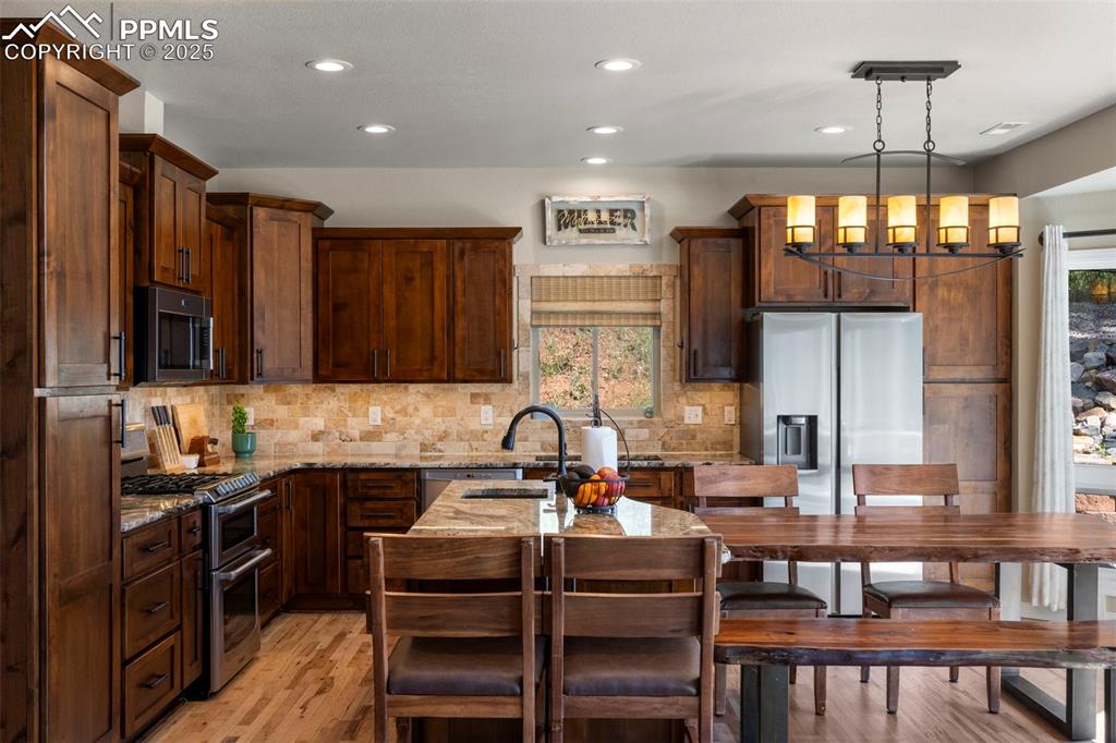 Image 7 of 46: Kitchen featuring light stone counters, stainless steel appliances, light w