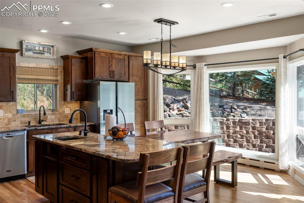 Image 8 of 46: Kitchen featuring dark stone counters, light wood-style flooring, pendant l