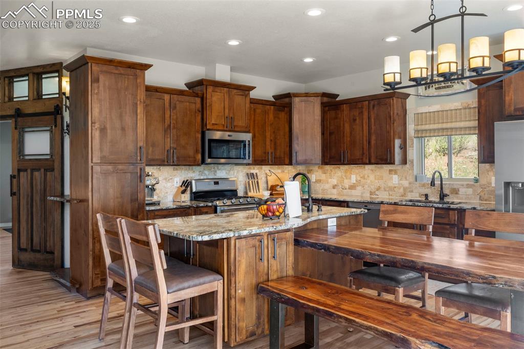 Image 9 of 46: Kitchen with light stone counters, a barn door, stainless steel appliances,