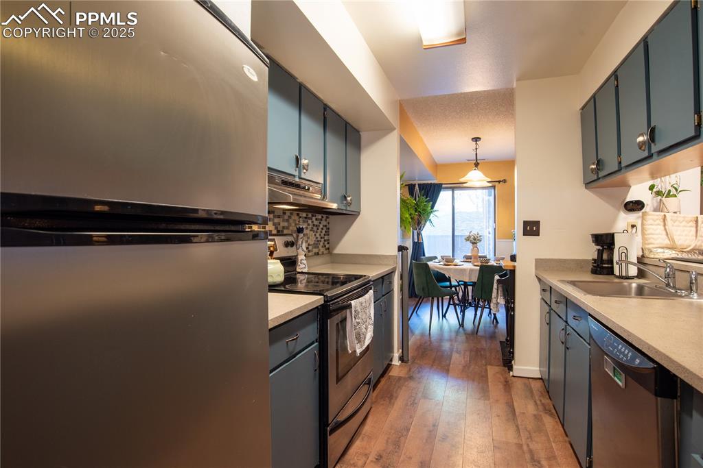Image 10 of 29: Kitchen with stainless steel appliances, backsplash, hanging light fixtures