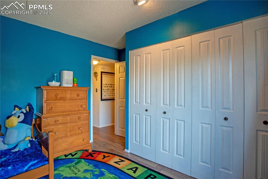 Image 17 of 29: Bedroom with a textured ceiling, a closet, and wood finished floors