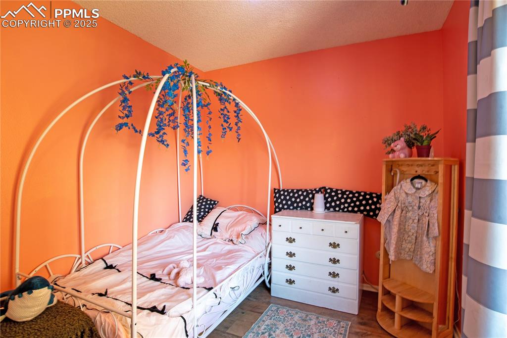 Image 19 of 29: Bedroom with a textured ceiling and wood finished floors