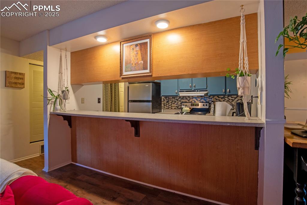 Image 8 of 29: Kitchen featuring blue cabinetry, stainless steel appliances, tasteful back