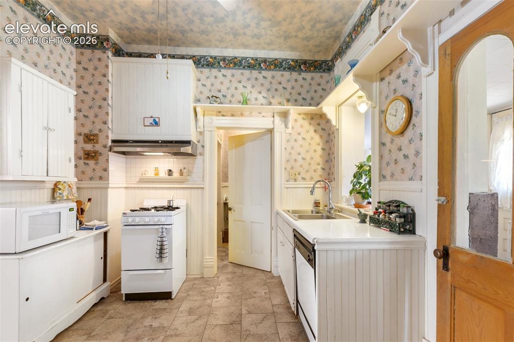 Image 17 of 29: Walk-out to the enclosed patio laundry room from the kitchen. Sunlight stre