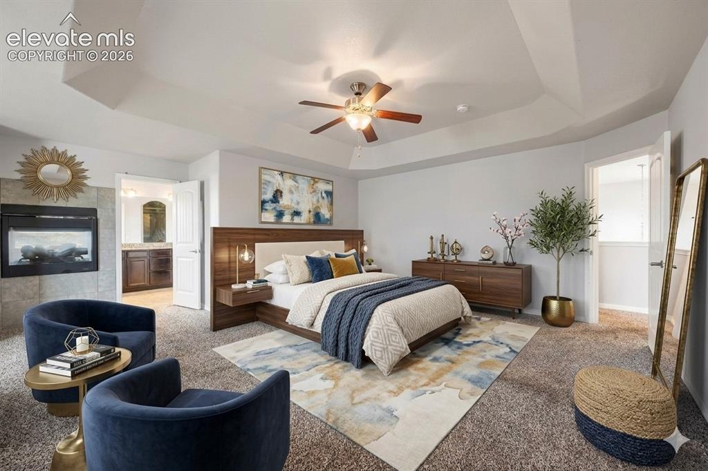 Image 13 of 41: Tray ceiling with a ceiling fan, wall-mounted electric fireplace with a til
