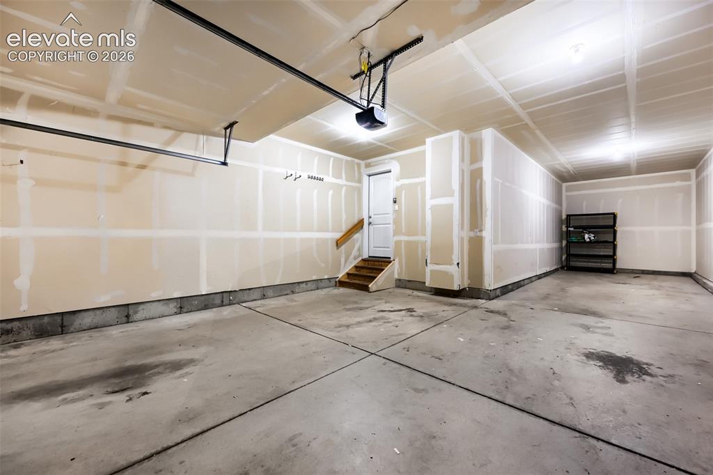 Image 35 of 41: Attached garage with concrete flooring, unfinished walls, and a built-in ga