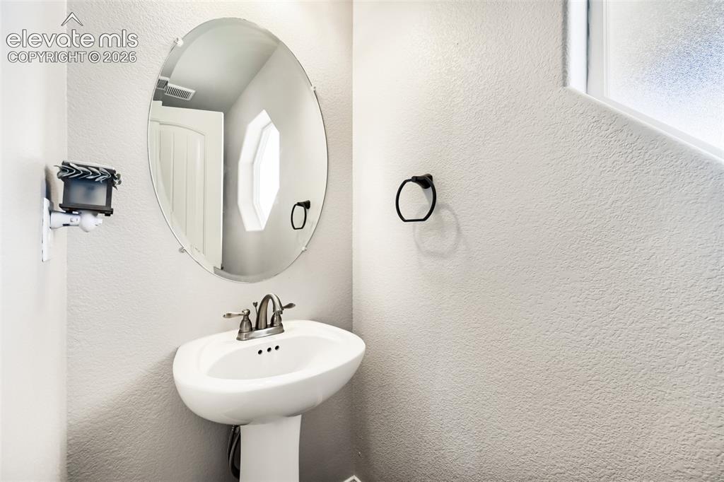 Image 5 of 41: Pedestal sink with a dual-handle faucet and oval mirror