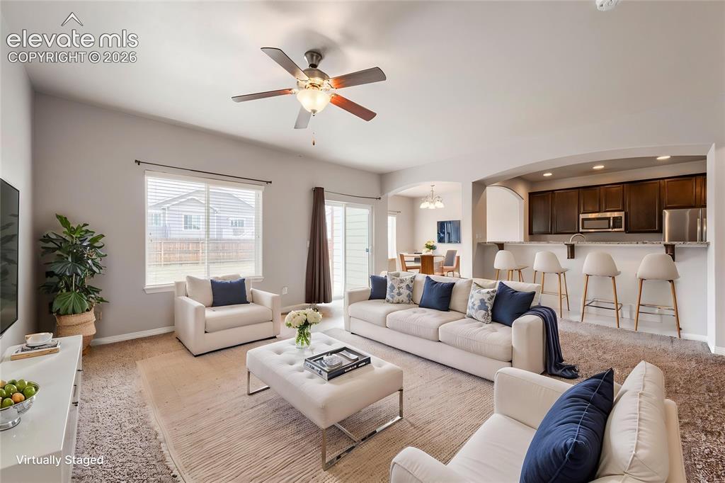Image 6 of 41: Open concept living area with vaulted ceilings, a ceiling fan, sliding glas