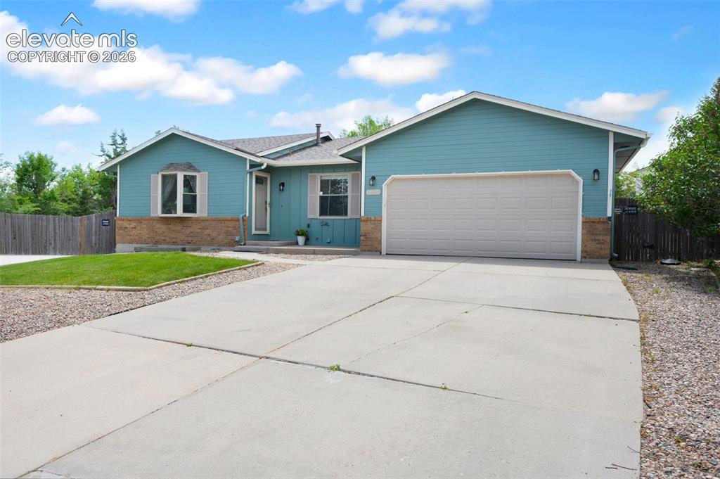 Image 1 of 50: Ranch-style home with brick siding, a garage, driveway, and board and batte