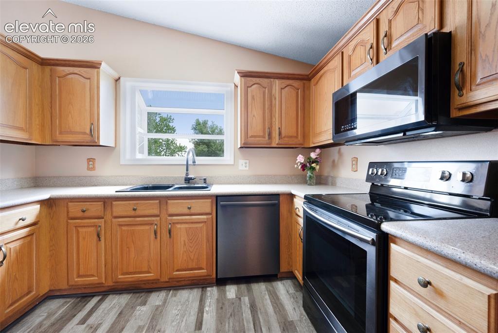 Image 13 of 50: Kitchen with appliances with stainless steel finishes, a sink, vaulted ceil