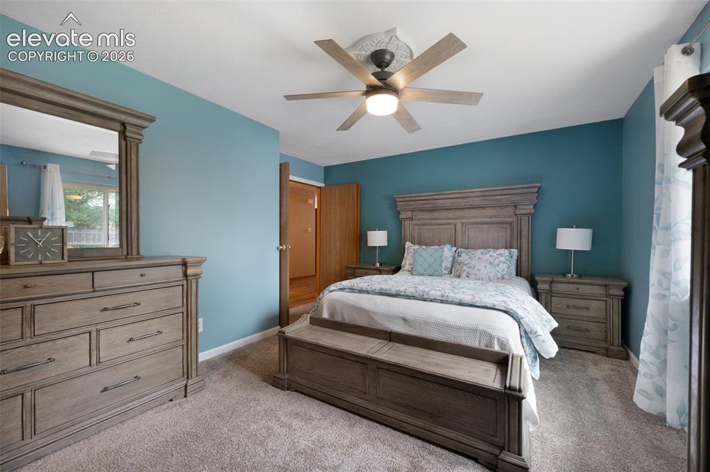 Image 17 of 50: Carpeted bedroom with a ceiling fan and baseboards