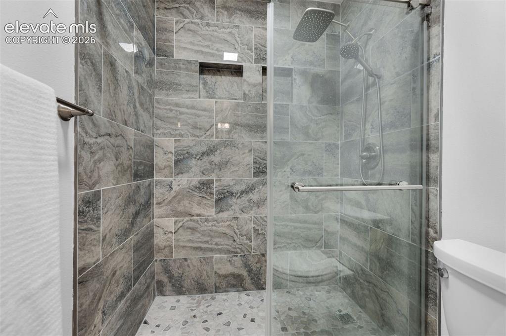 Image 22 of 50: Walk-in shower featuring glass enclosure, large format tile walls, pebble-f