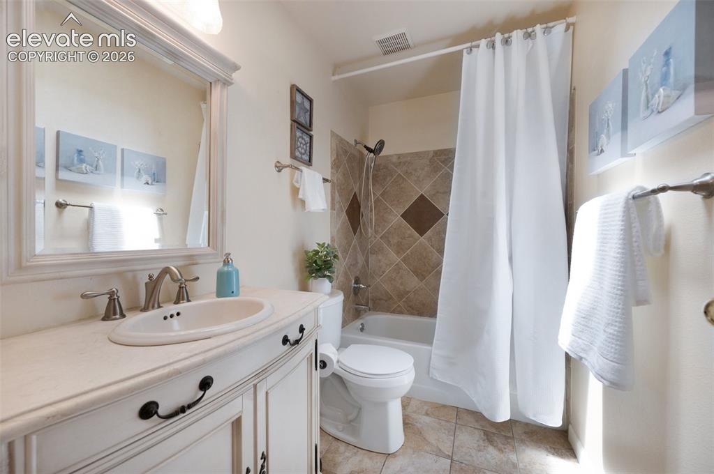Image 25 of 50: Bathroom with toilet, shower / tub combo with curtain, and vanity. Skylight