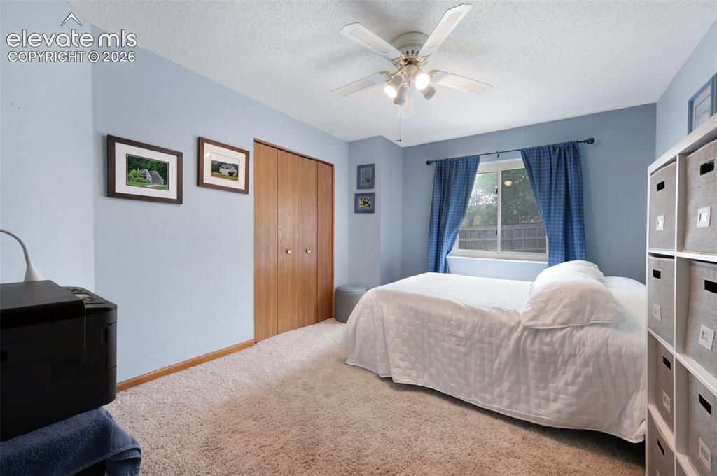 Image 26 of 50: Bedroom with carpet, a textured ceiling, a closet, and a ceiling fan