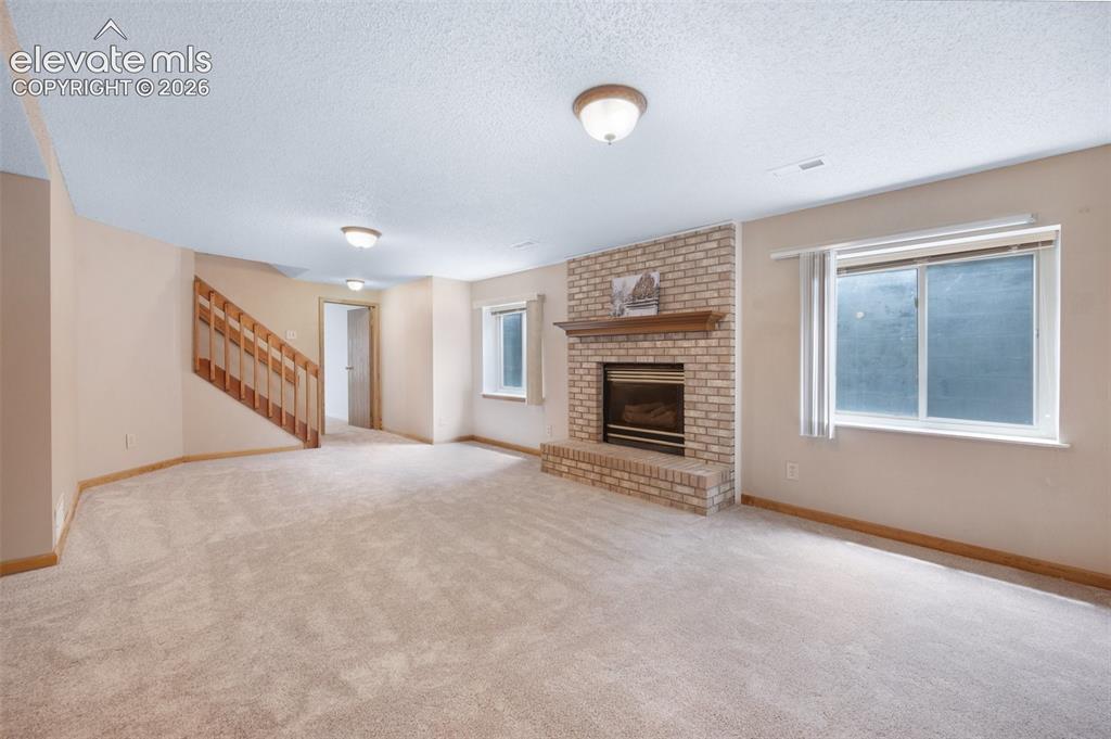 Image 31 of 50: Unfurnished living room with stairway, a textured ceiling, plenty of natura