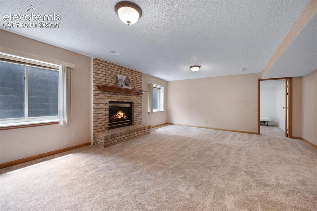 Image 32 of 50: Unfurnished living room featuring a textured ceiling, carpet flooring, a br