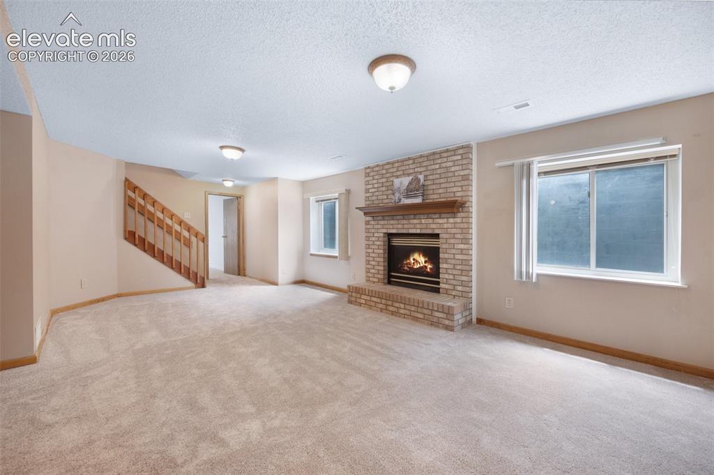 Image 35 of 50: Unfurnished living room featuring a textured ceiling, a brick fireplace, he