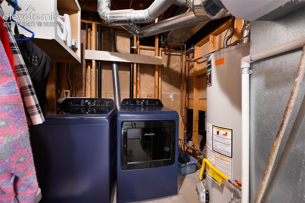Image 38 of 50: Clothes washing area featuring water heater and washer and clothes dryer