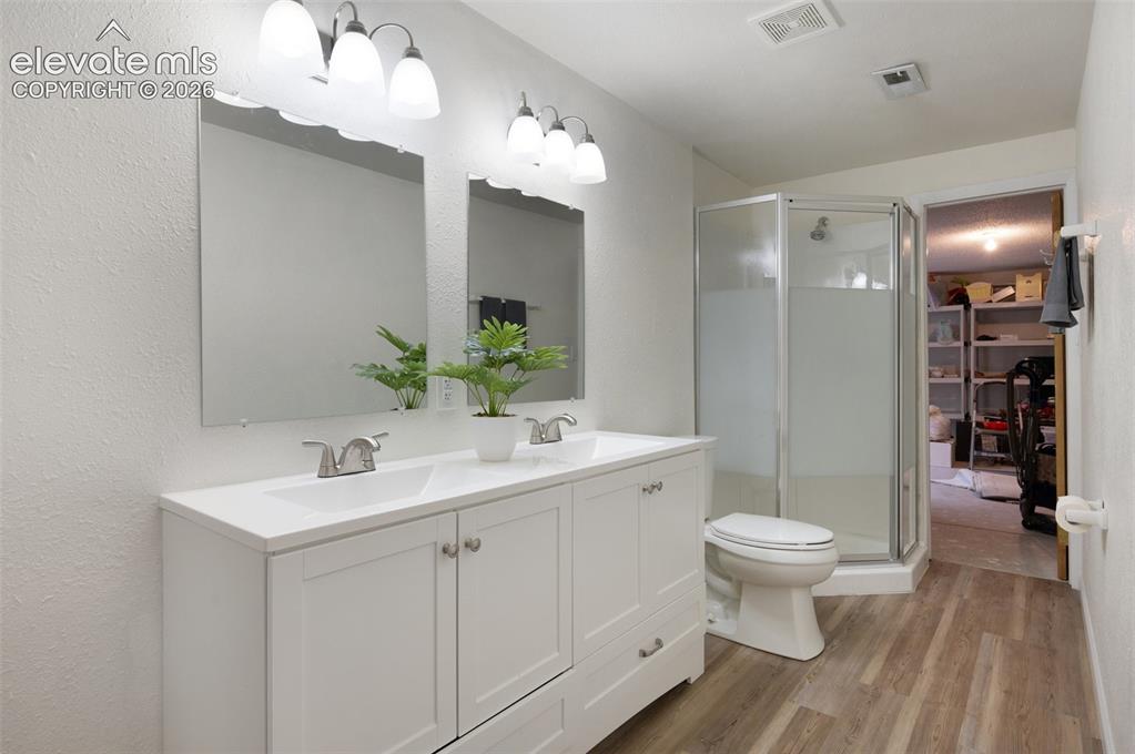 Image 39 of 50: Bathroom featuring wood finished floors, a shower stall, double vanity, toi