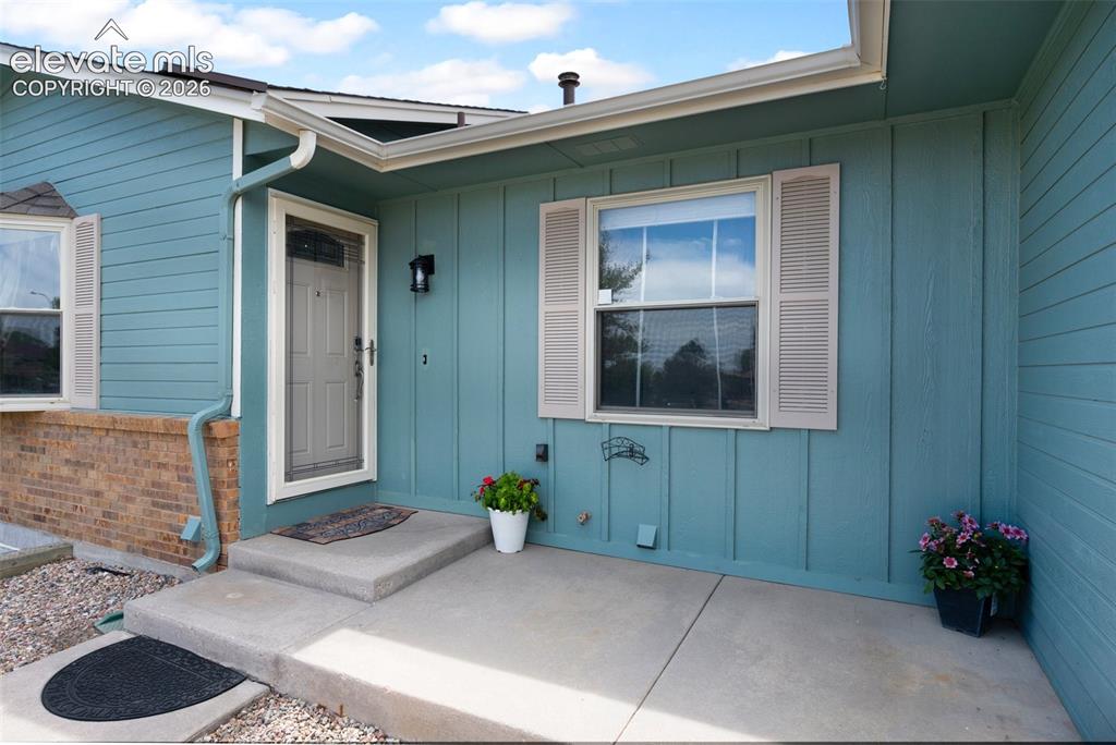 Image 4 of 50: Entrance to property with board and batten siding, brick siding, and a pati