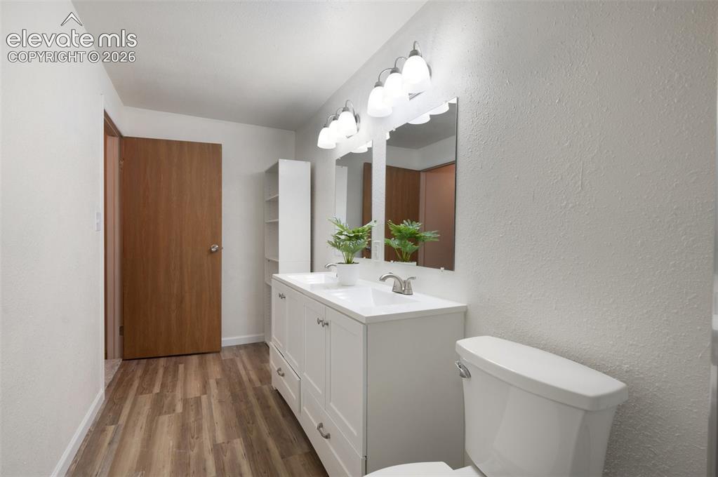 Image 41 of 50: Bathroom featuring wood finished floors, toilet, vanity, and baseboards