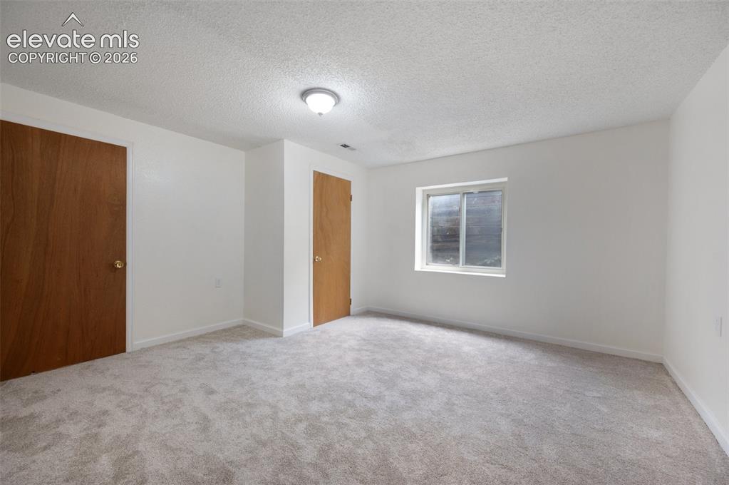 Image 43 of 50: Unfurnished bedroom featuring carpet floors, a textured ceiling, and basebo