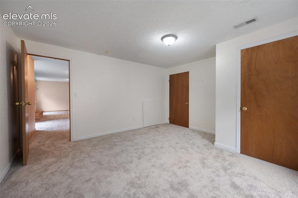 Image 44 of 50: Unfurnished bedroom featuring carpet flooring, a textured ceiling, and base