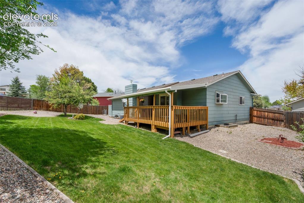 Image 46 of 50: Rear view of property featuring a wooden deck and a chimney