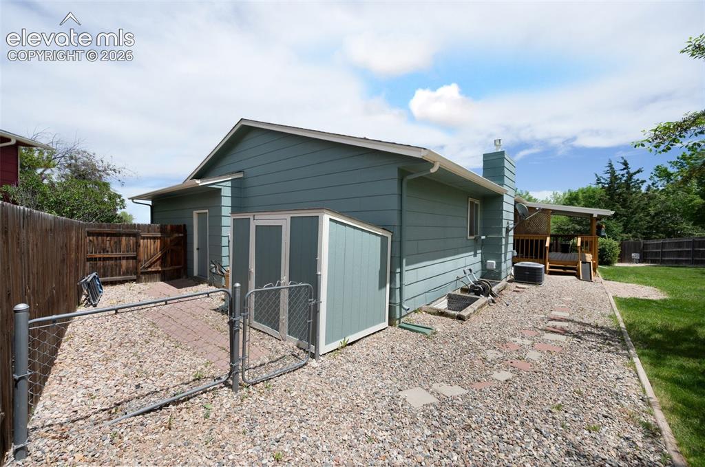Image 49 of 50: View of outbuilding with a gate, a fenced backyard, and central air conditi
