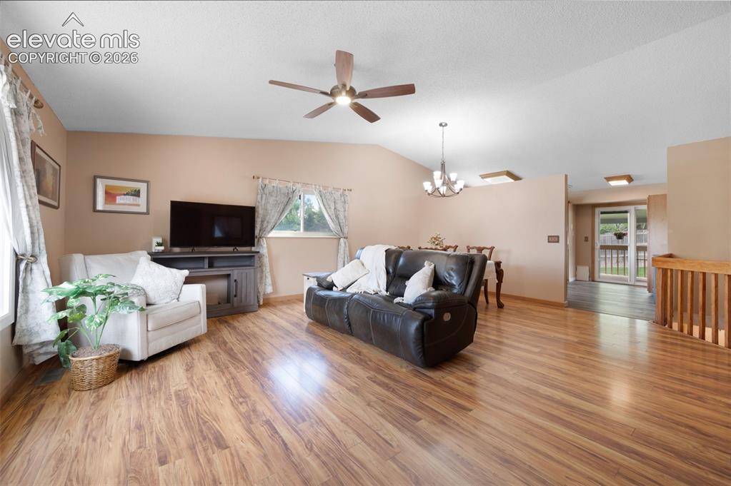 Image 5 of 50: Living area featuring a ceiling fan, light wood finished floors, a chandeli
