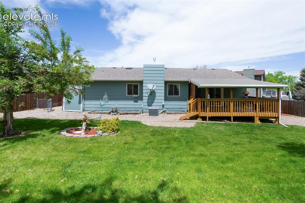 Image 50 of 50: Rear view of house featuring a wooden deck, a chimney, a shingled roof, and