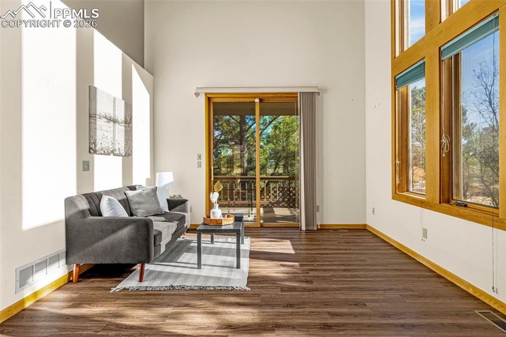 Image 15 of 47: Living area featuring dark wood-style floors, a high ceiling, and healthy a