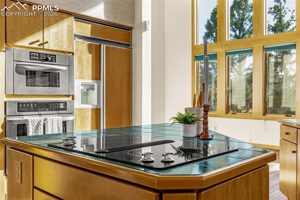Image 18 of 47: Kitchen with stainless steel double oven, black electric cooktop, paneled r
