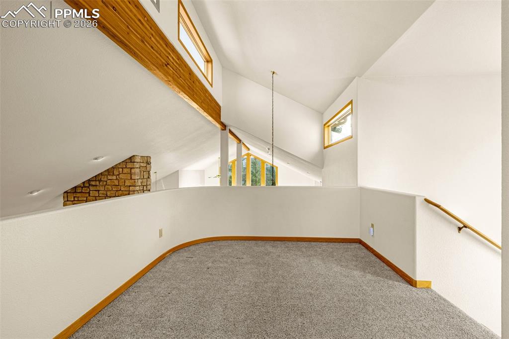 Image 22 of 47: Unfurnished room featuring carpet and vaulted ceiling with beams