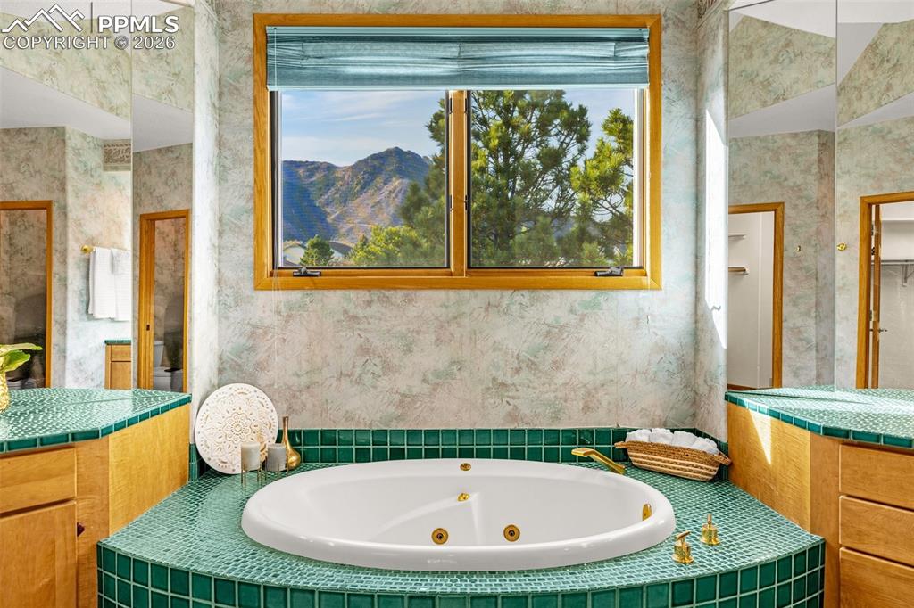 Image 28 of 47: Bathroom with a whirlpool tub, vanity, and wallpapered walls