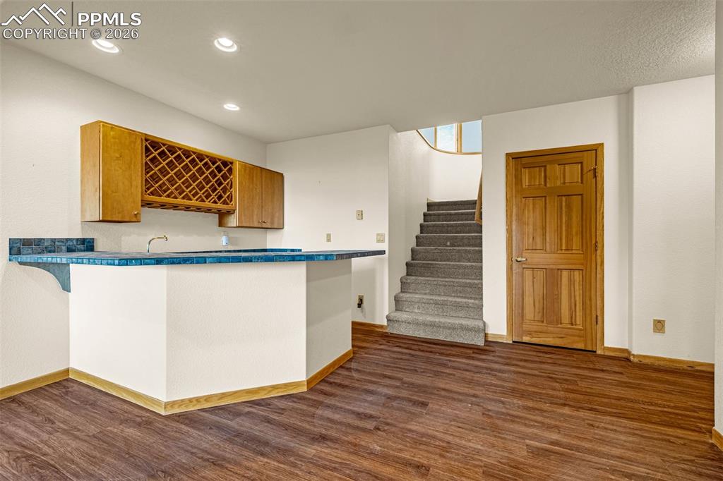 Image 35 of 47: Bar area featuring dark wood-type flooring, wood finish cabinetry, recessed