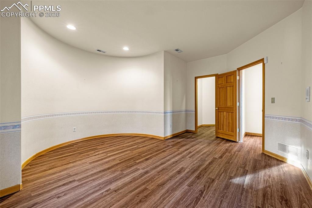 Image 39 of 47: Empty room with dark wood finished floors and recessed lighting