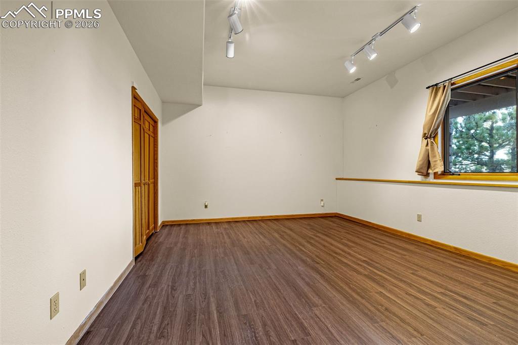 Image 41 of 47: Empty room with dark wood-type flooring and baseboards