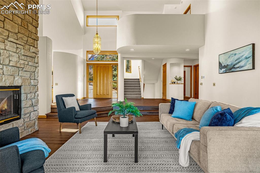 Image 8 of 47: Living area featuring wood finished floors, a fireplace, a high ceiling, an