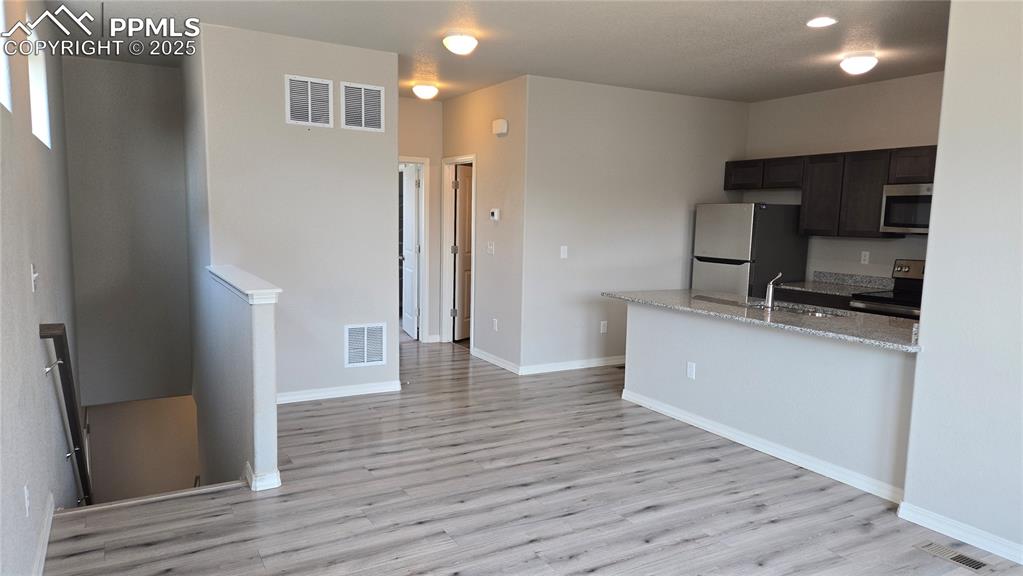 Image 10 of 29: Dining area and kitchen with light wood-type flooring, stainless steel appl