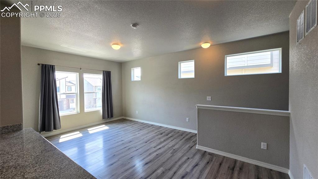 Image 14 of 29: Unfurnished dining area featuring a textured ceiling and wood finished floo