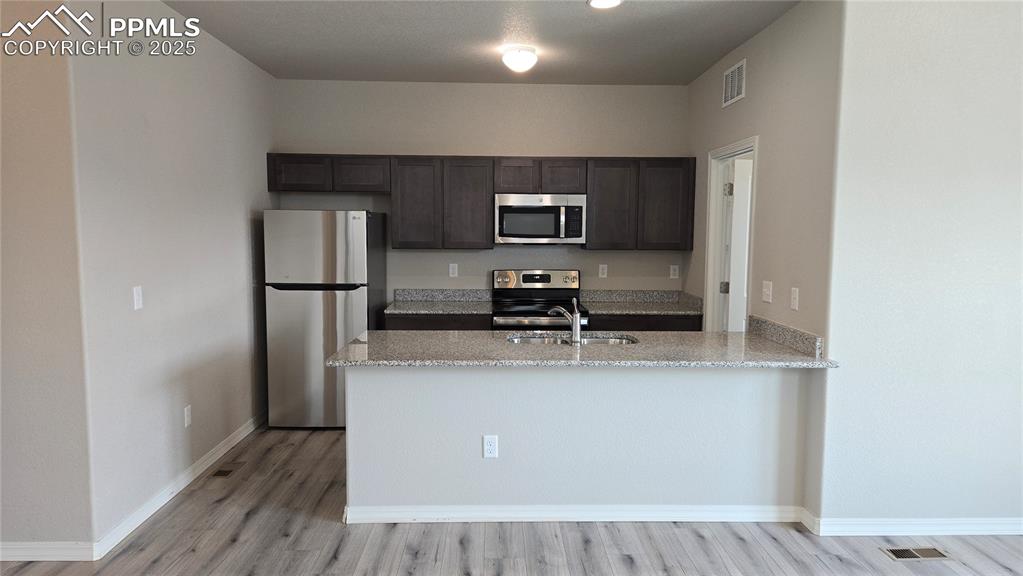 Image 15 of 29: Kitchen featuring appliances with stainless steel finishes, a breakfast bar