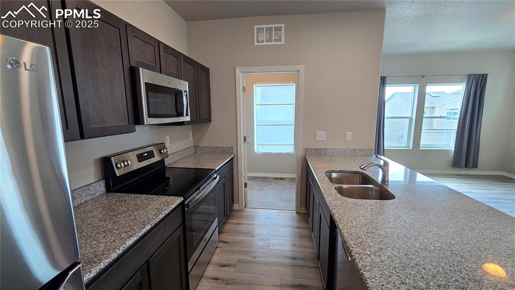 Image 16 of 29: Kitchen featuring appliances with stainless steel finishes, light stone cou