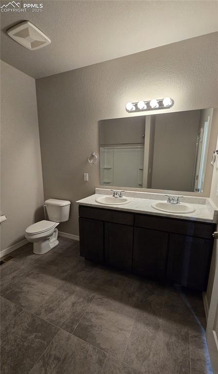 Image 21 of 29: Upper level full bath with a textured wall and double vanity