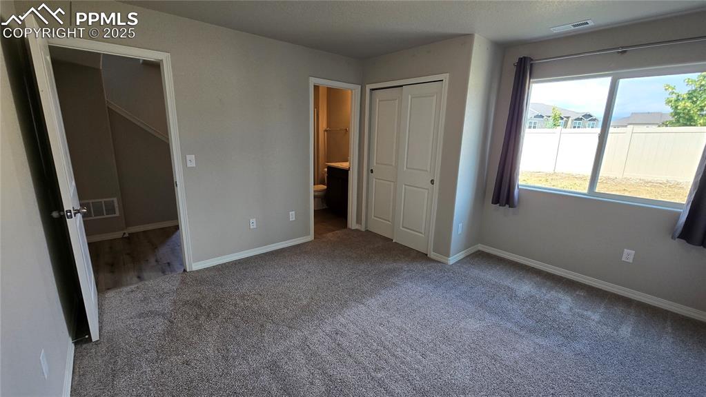 Image 6 of 29: Main level bedroom with carpet, connected bathroom, and closet