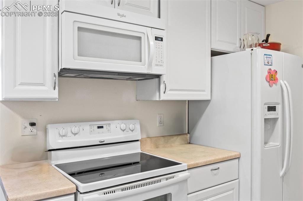 Image 10 of 21: Kitchen with white appliances, white cabinets, and light countertops