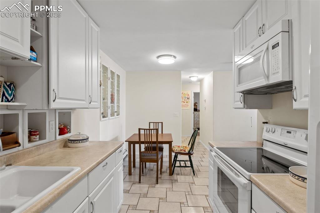 Image 12 of 21: Kitchen with white appliances, white cabinets, light countertops, and open 