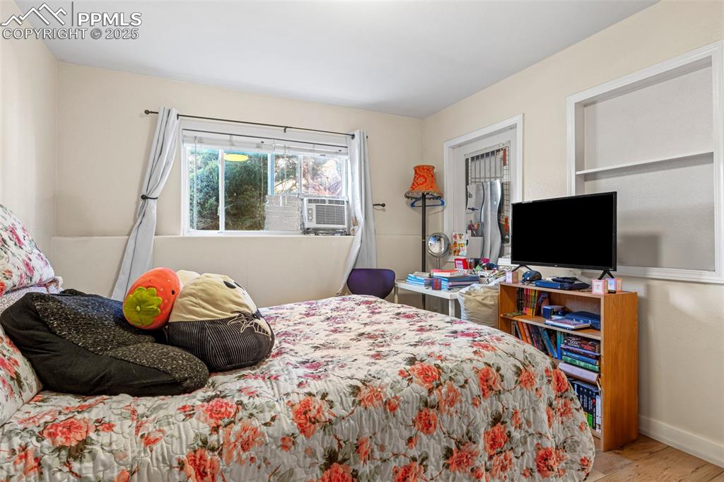 Image 13 of 21: Bedroom with wood finished floors and cooling unit